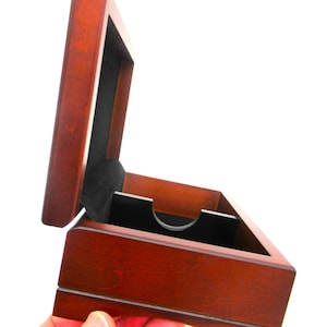 May include: A dark brown wooden box with a hinged lid that is open. The interior of the box is lined with black fabric and features a central black divider with a semi-circular cutout. The box has a smooth finish and a rectangular shape.