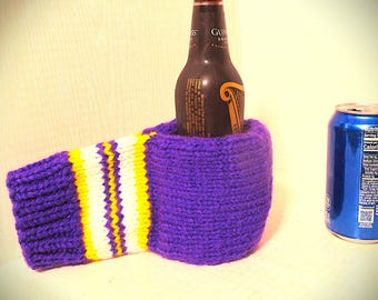May include: Purple and yellow striped knitted bottle cozy with a brown beer bottle inside. A blue can is in the background.