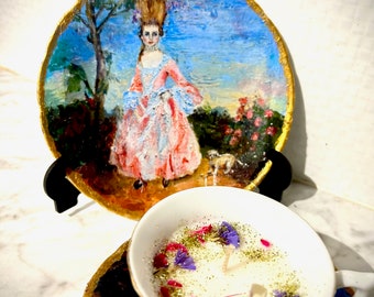 Scented teacup candle with matching saucer and plate with embellished prints of artist's painting