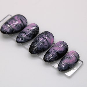 May include: Set of six false nails with a pink and black marbled design and silver glitter accents.