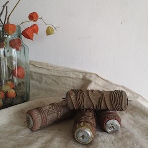 Può includere: Quattro rulli di vernice vintage con manici in legno e estremità metalliche. I rulli sono ricoperti da un materiale marrone testurizzato. I rulli sono disposti in una pila su una superficie di tessuto bianco.