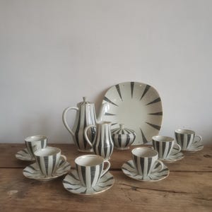 May include: A vintage tea set with black and white striped pattern. The set includes a teapot, creamer, sugar bowl, and six cups and saucers.