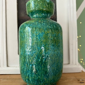 Può includere: Un vaso in ceramica verde e giallo con una glassa macchiettata. Il vaso ha un corpo arrotondato e un'apertura leggermente svasata.