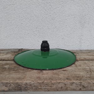 Peut inclure: Un abat-jour circulaire en métal vert brillant présentant une surface lisse légèrement bombée et un composant de douille cylindrique noir foncé centré au sommet. Les bords de l'abat-jour sont finis avec un bord sombre et fin.
