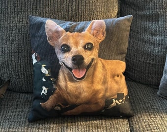 May include: A brown and tan chihuahua dog with a big smile on a black and white floral pillow.