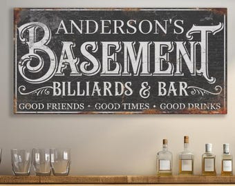 May include: A black and white sign with the text "Anderson's Basement Billiards & Bar" and the tagline "Good Friends - Good Times - Good Drinks".