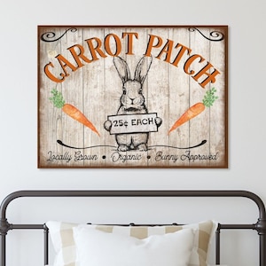 Puede incluir: Un letrero de estilo vintage con el texto "Carrot Patch" en letras naranjas sobre un fondo de madera marrón. Un conejo de dibujos animados sostiene un letrero que dice "25¢ EACH". El letrero también dice "Locally Grown, Organic, Bunny Approved".
