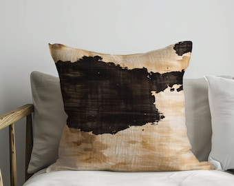 May include: A throw pillow with a brown and beige abstract design. The pillow is on a white couch with a wooden armrest.