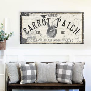 May include: A rectangular wall sign with a distressed white finish and black lettering. The text reads THUMPER'S CARROT PATCH EST. 1957 LOCALLY GROWN. A black and white illustration of a rabbit head is centered between the words CARROT and PATCH.