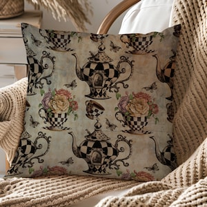Pu&ograve; includere: Un cuscino decorativo con un design di ispirazione vintage che presenta teiere e tazze a scacchi in bianco e nero con accenti floreali. Lo sfondo &egrave; blu chiaro con una texture usurata.