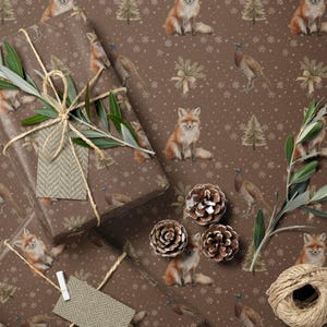 Op de afbeelding: Bruin cadeaupapier met een herhaald patroon van vossen, fazanten en kerstbomen. Verschillende ingepakte cadeaus zijn versierd met touw, takjes groen en labels. Pijnappels en een schaar zijn ook zichtbaar.