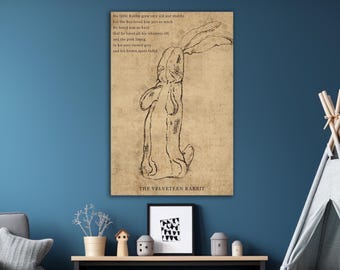 Op de afbeelding: Een rechthoekige wandkunstprint op een beige, getextureerde achtergrond met een zwarte lijntekening van een konijn van achteren gezien. De tekst luidt: The little Rabbit grew very old and shabby, but the Boy loved him just as much. The Velveteen Rabbit.