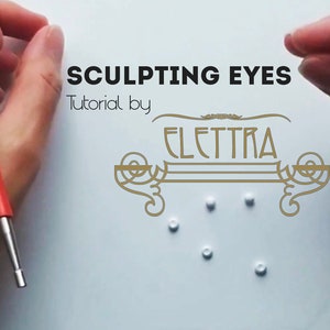 Può includere: Una superficie bianca con il testo "SCULPTING EYES Tutorial by ELETTRA" in lettere dorate. Ci sono sei perline bianche sparse sulla superficie.