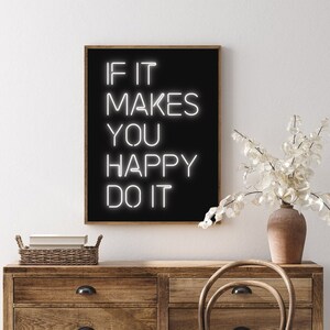 May include: A framed black art print with the text "IF IT MAKES YOU HAPPY DO IT" in white neon-style lettering. The print is displayed above a wooden dresser with a vase of white flowers.