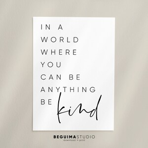 May include: Black and white typography print with the text "In a world where you can be anything be kind". The text is in a modern, minimalist font style.