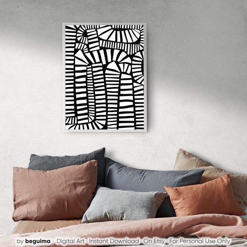 May include: A framed black and white abstract art print. The artwork has a geometric design with vertical and curved lines. The print is displayed above a bed with various coloured pillows and a pink blanket. The text "by beguima" is visible at the bottom.