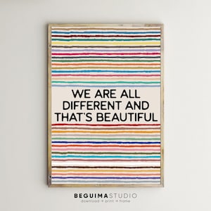 Puede incluir: Una impresión artística enmarcada con un marco de madera clara. La obra presenta rayas horizontales en varios colores encima y debajo de un rectángulo color crema con el texto "WE ARE ALL DIFFERENT AND THAT'S BEAUTIFUL" en negro. La parte inferior de la impresión tiene el texto "BEGUIMASTUDIO".