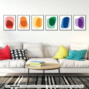 May include: Set of six abstract art prints featuring colorful overlapping shapes in a rainbow color scheme. The prints are framed in black and displayed on a white wall above a white couch.