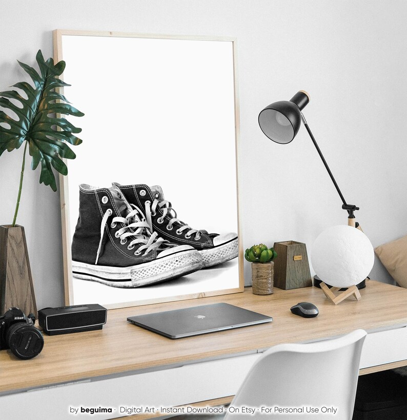 Puede incluir: Impresi&oacute;n en blanco y negro enmarcada de zapatillas altas negras con cordones blancos y suela de goma blanca. La impresi&oacute;n est&aacute; sobre un escritorio de madera con una l&aacute;mpara, un port&aacute;til y otros elementos decorativos.