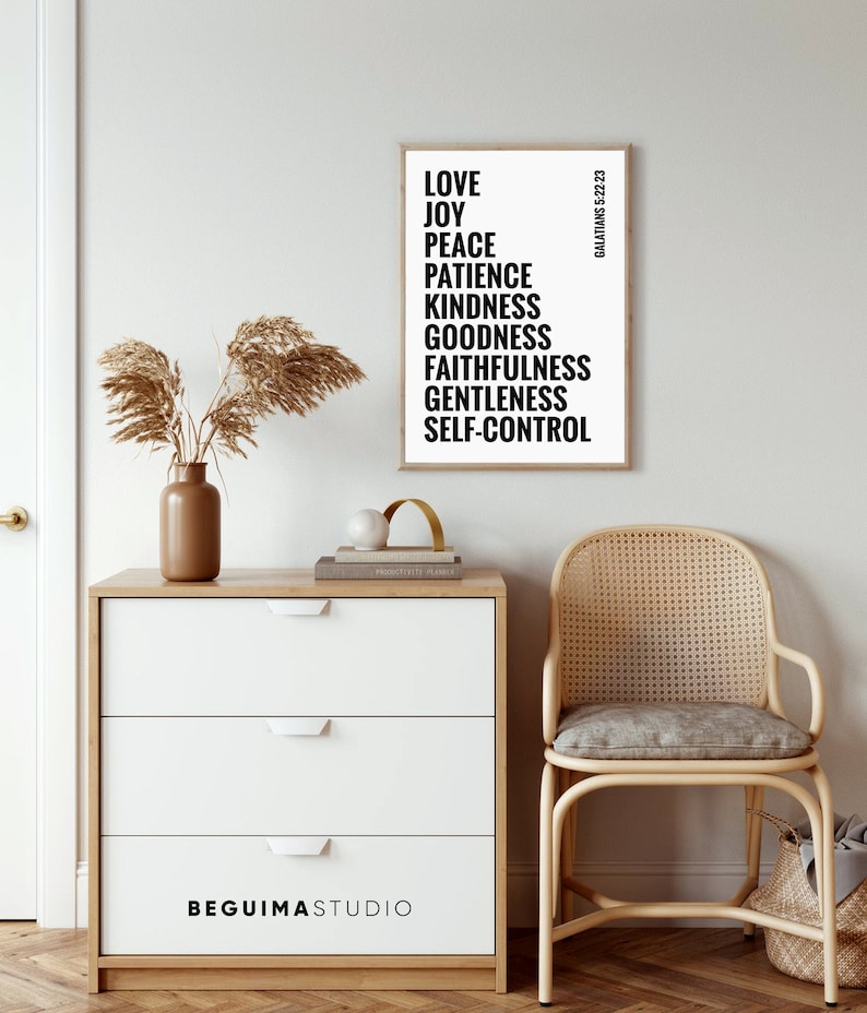 May include: A black and white printable wall art print with the text "LOVE, JOY, PEACE, PATIENCE, KINDNESS, GOODNESS, FAITHFULNESS, GENTLENESS, SELF-CONTROL" and the text "GALATIANS 5:22-23" in a smaller font. The print is framed and hanging on a white wall.