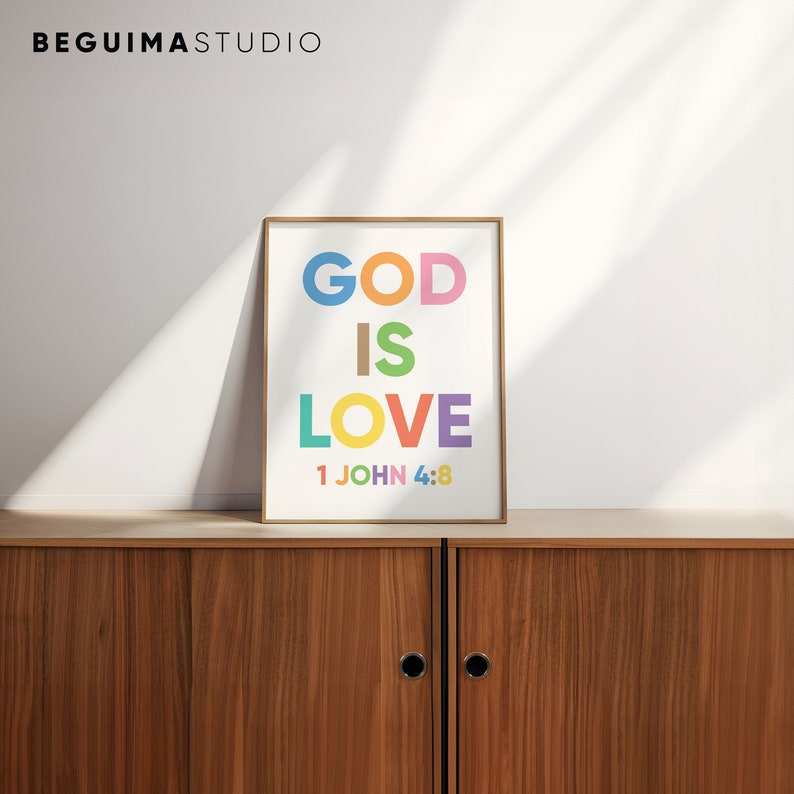 May include: A framed art print with the words "GOD IS LOVE" in colorful block letters. The text "1 JOHN 4:8" is below the main text. The print is displayed on a wooden cabinet.