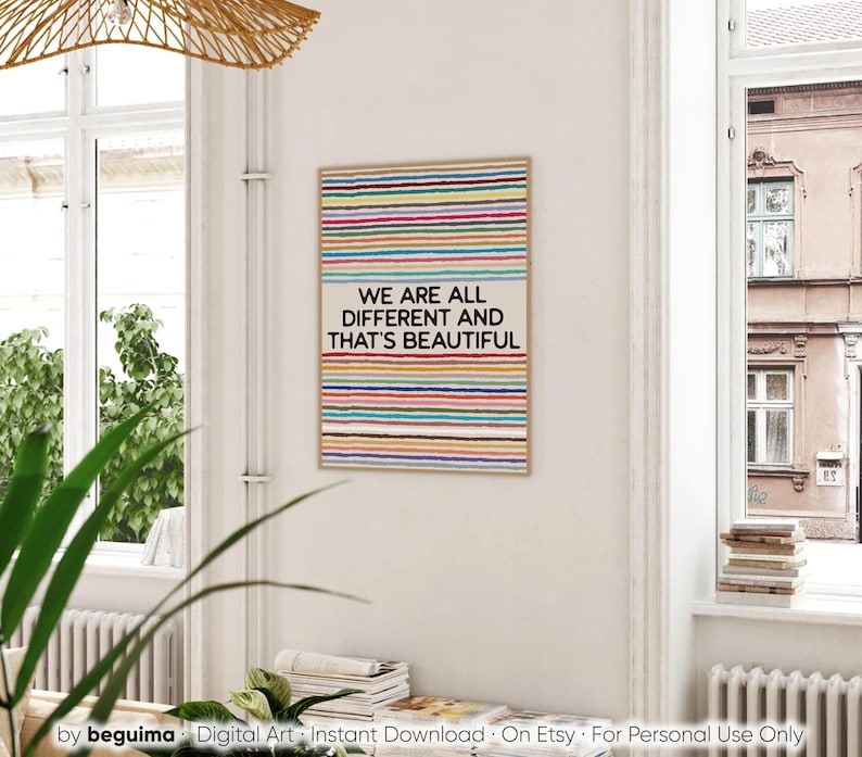 May include: A framed art print featuring a beige background and vibrant horizontal stripes. The text "WE ARE ALL DIFFERENT AND THAT'S BEAUTIFUL" is displayed. The artwork is in a room with natural light, near a window.