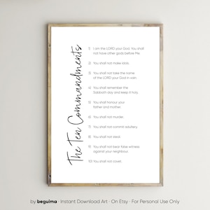 May include: A framed print displaying the Ten Commandments in black script on a white background. The text is arranged in a list format, with each commandment numbered. The frame is a light brown color. The words "The Ten Commandments" are written vertically on the left side.