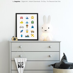 May include: A framed print featuring colorful illustrations of various vehicles, including a car, boat, bus, submarine, airplane, hot air balloon, rocket, train, truck, scooter, ship, and airplane. The print is displayed on a gray dresser with a bunny lamp and a banner that says "DREAM BIG".