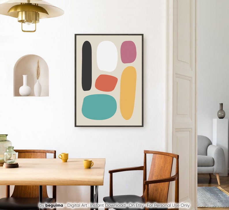 May include: Abstract art print featuring a black framed artwork with colorful, rounded shapes. The shapes include black, white, red, pink, yellow, and teal on a beige background. The artwork hangs on a white wall in a dining room setting.