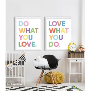 May include: Two framed art prints with the phrases "DO WHAT YOU LOVE" and "LOVE WHAT YOU DO" in colorful block letters. The room features a black chair, a yellow pouf, a crib, and a white side table with a yellow clock and a teddy bear.