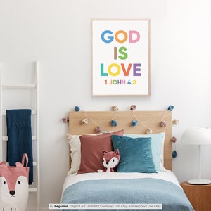 May include: A framed print with the words "GOD IS LOVE" in colorful letters, with "1 JOHN 4:8" below. The print hangs above a bed with pillows and a stuffed fox. A white ladder and a fox-themed storage basket are also visible.