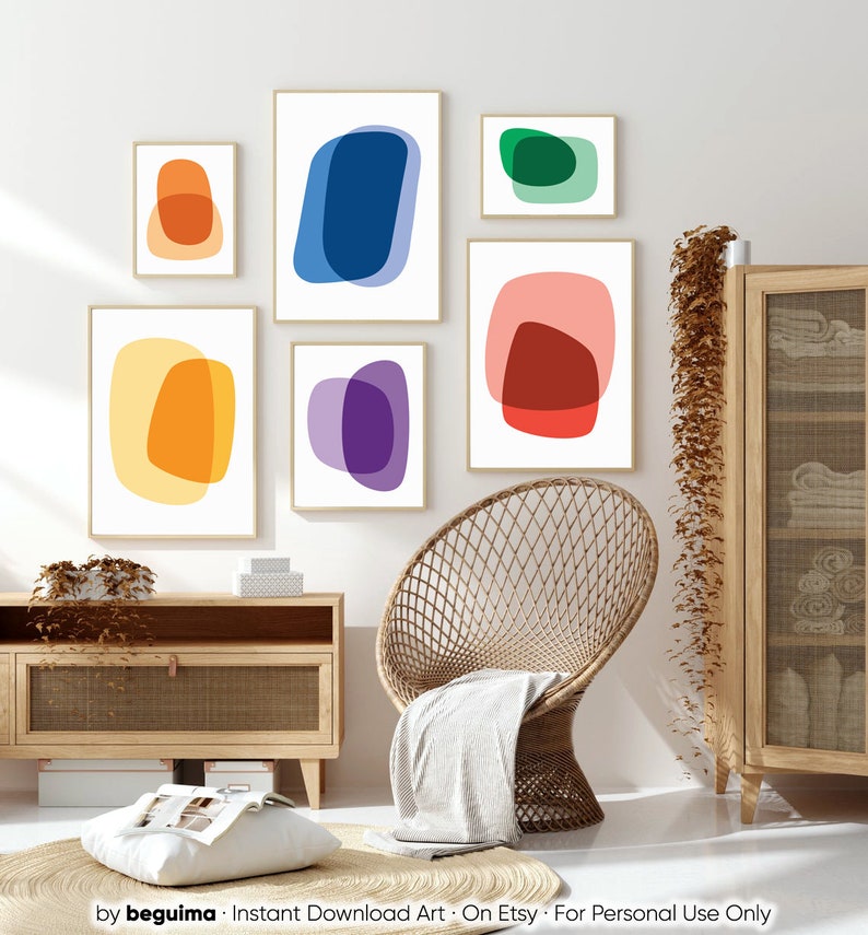 May include: Set of six abstract art prints featuring overlapping shapes in various colors, including yellow, orange, red, blue, green, and purple. The prints are displayed on a white wall in a living room setting.