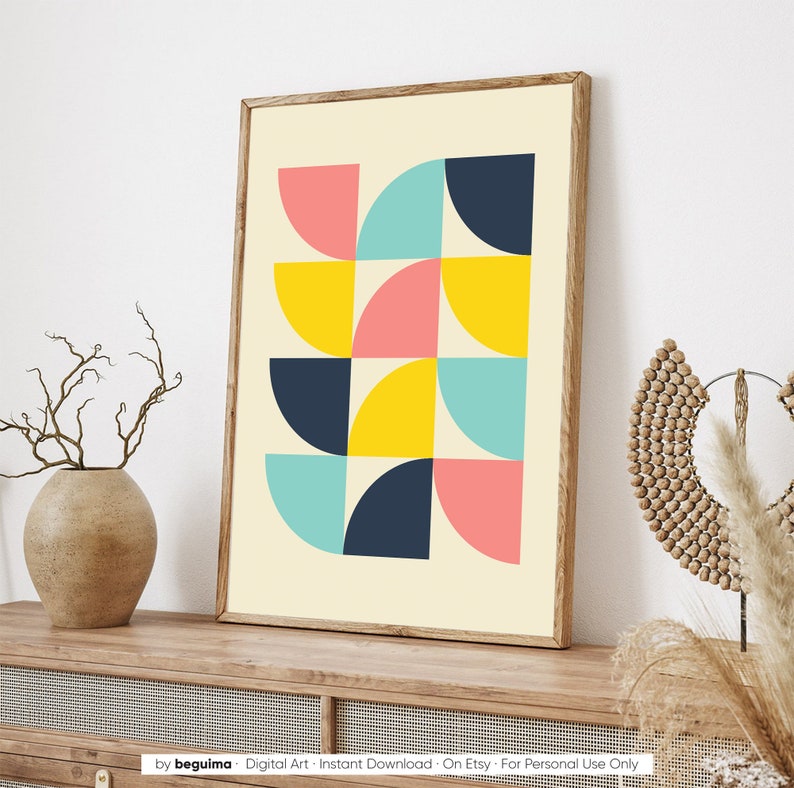 Puede incluir: L&aacute;mina de arte abstracto con un dise&ntilde;o geom&eacute;trico de formas de cuarto de c&iacute;rculo en rosa, amarillo, turquesa y azul marino sobre un fondo crema. La obra est&aacute; enmarcada en un marco de madera marr&oacute;n claro y expuesta sobre una superficie de madera.