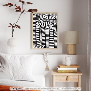 May include: Abstract black and white art print in a natural wood frame. The artwork features a geometric design of vertical and curved lines. The print is displayed above a white bed with a decorative pillow and a small wooden side table.