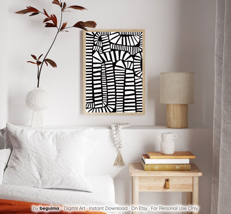 May include: Abstract black and white art print in a natural wood frame. The artwork features a geometric design of vertical and curved lines. The print is displayed above a white bed with a decorative pillow and a small wooden side table.