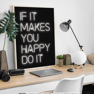 May include: A black framed print with the words "IF IT MAKES YOU HAPPY DO IT" in white neon-style lettering. The print is on a wooden desk with a laptop, lamp, and other decorative items.