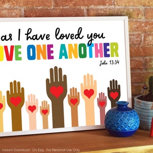 May include: A white printable sign with the text "as I have loved you LOVE ONE ANOTHER John 13:34" in rainbow colors. The sign features a row of colorful hands with red hearts in the palms.