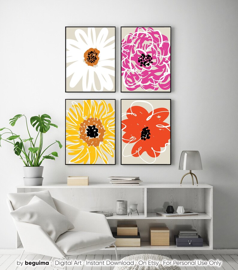 May include: Four framed floral art prints. Each print features a large, stylized flower in white, pink, yellow, and orange against a neutral background. The artwork is displayed above a white shelf with decorative items and a modern chair.