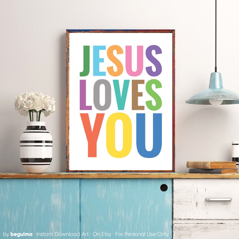Może przedstawiać: Kolorowy wydruk z tekstem "JESUS LOVES YOU" w tęczy kolor&oacute;w. Wydruk jest oprawiony w brązową drewnianą ramę i wisi na białej ścianie.
