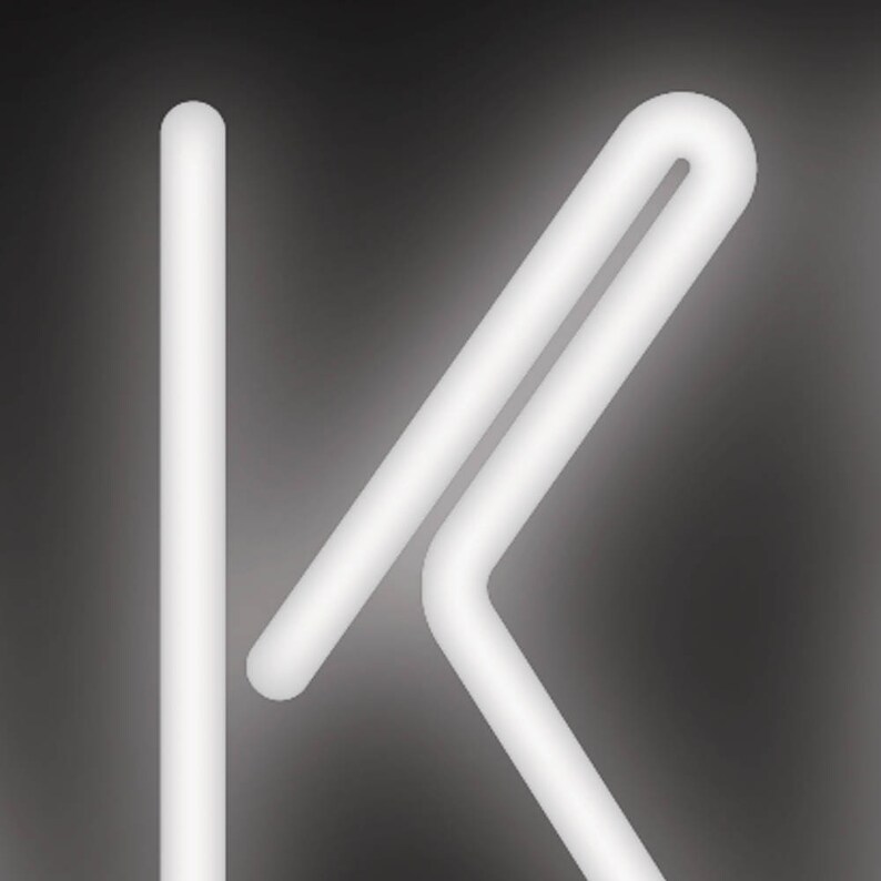 May include: A white, glowing neon light in the shape of the letter "K" against a dark gray background. The "K" is formed by a straight vertical line and a connected, angled design.