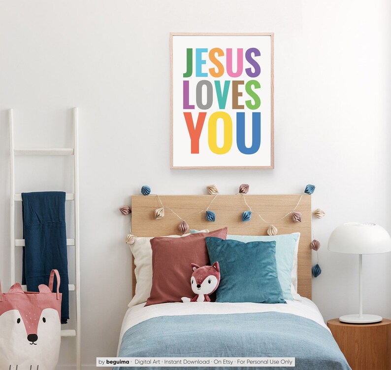 Może przedstawiać: Kolorowy, drukowany obraz na ścianę z tekstem "JESUS LOVES YOU" w tęczy kolor&oacute;w. Obraz jest wyświetlany w sypialni z ł&oacute;żkiem, poduszkami i lampą.