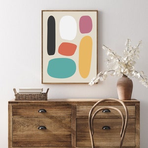 May include: Abstract art print featuring a beige background with colorful, rounded shapes in black, white, red-orange, teal, pink, and yellow. The artwork is framed in a brown wooden frame and displayed above a wooden dresser. The text "by beguima - Digital Art - Instant Download - On Etsy - For Personal Use Only" is at the bottom.