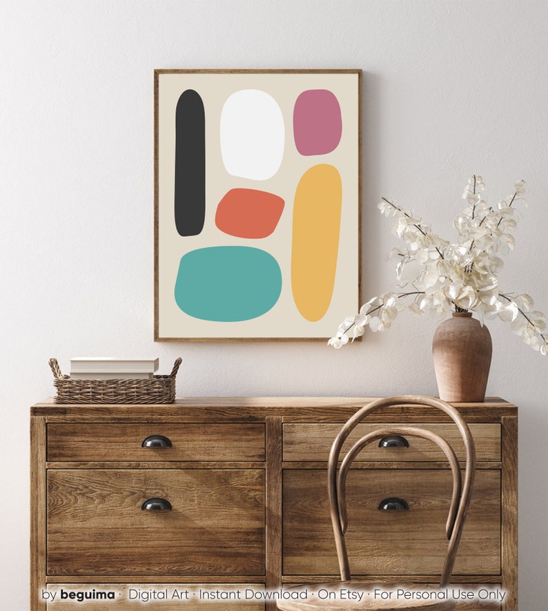 May include: Abstract art print featuring a beige background with colorful, rounded shapes in black, white, red-orange, teal, pink, and yellow. The artwork is framed in a brown wooden frame and displayed above a wooden dresser. The text "by beguima - Digital Art - Instant Download - On Etsy - For Personal Use Only" is at the bottom.