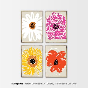 May include: Four framed floral art prints. Each print features a different abstract flower design in bright colors: white, pink, yellow, and orange. The flowers have black and brown centers and are set against a neutral background. The frames are a light wood color.