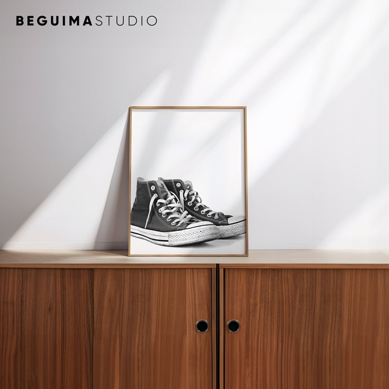 Puede incluir: Una impresi&oacute;n enmarcada con un par de zapatillas altas negras con cordones blancos y suela blanca. La impresi&oacute;n se exhibe en un mueble de madera. El texto "BEGUIMA STUDIO" est&aacute; en la parte superior.