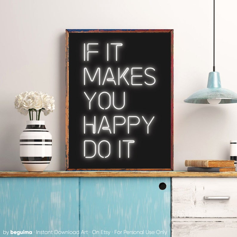 May include: A framed black sign with the text "IF IT MAKES YOU HAPPY DO IT" in white neon-style lettering. The sign is on a blue cabinet with a white vase and flowers. A light blue pendant lamp hangs from the ceiling.