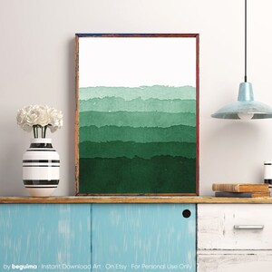 May include: A framed art print featuring a watercolor design of layered green hues. The artwork transitions from white at the top to deep green at the bottom. The frame is a warm brown with a touch of blue at the top.
