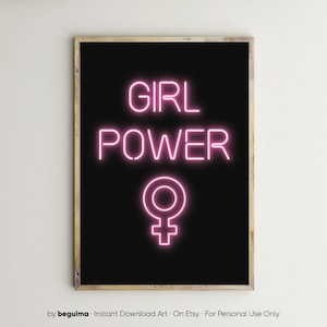 May include: A framed art print featuring the words "GIRL POWER" in bright pink neon-style lettering, and a pink female symbol, against a black background. The print is in a wooden frame.