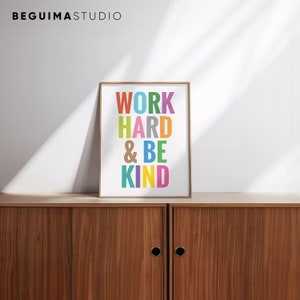 May include: A framed print with the text "WORK HARD & BE KIND" in colorful letters on a white background. The frame is a light wood color.