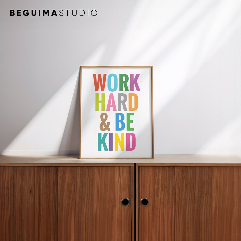 May include: A framed print with the text "WORK HARD & BE KIND" in colorful letters on a white background. The frame is a light wood color.
